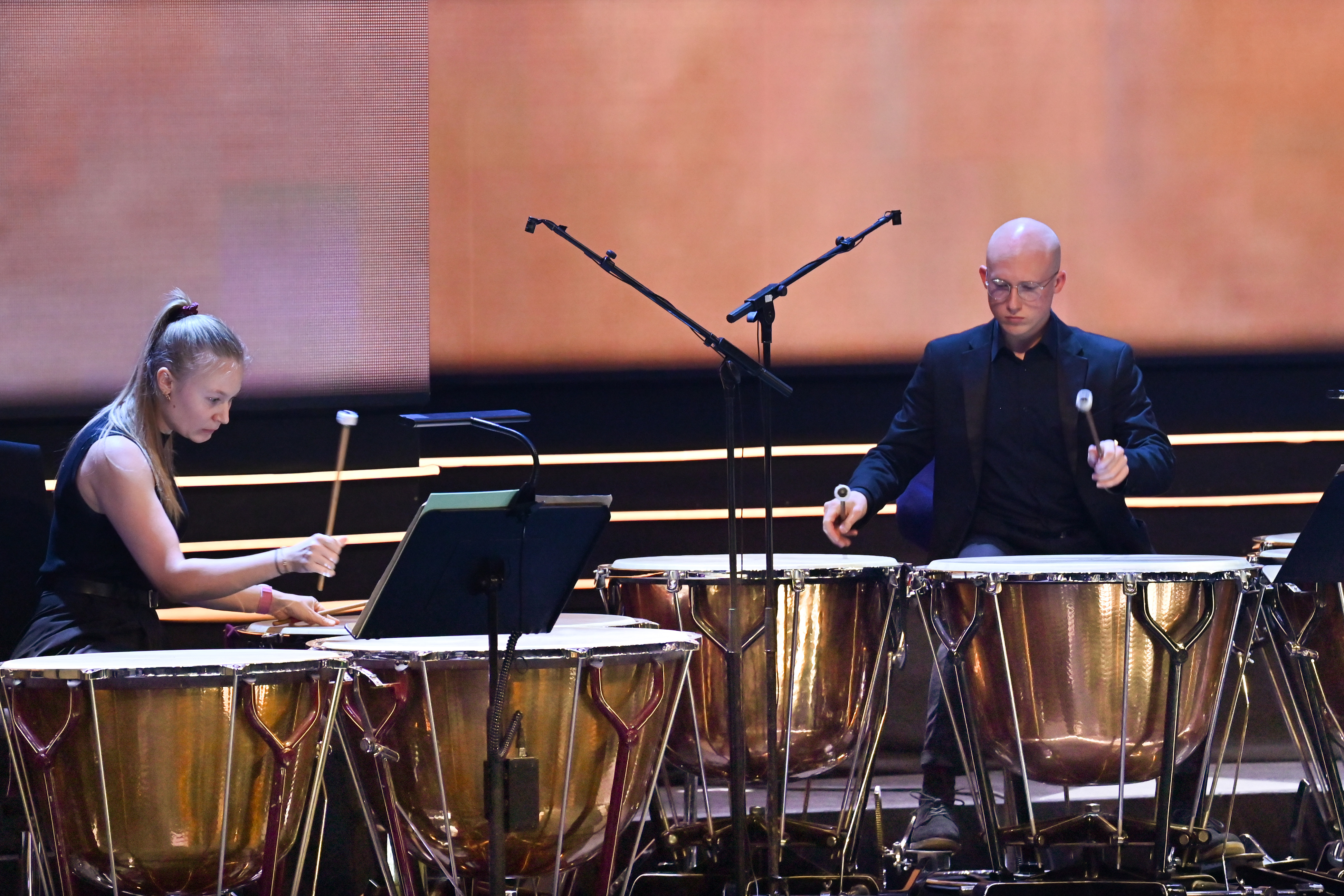 Two students playing on the timpanis in the percussion section, on stage at the Royal Albert Hall.